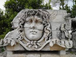 A carved marble Medusa head from the frieze of the Temple of Apollo at Didyma, her hair coiling into serpents.